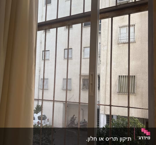 חלון עם סורגים ונוף לבניין ממול